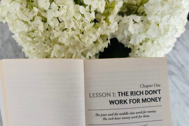 Open book Rich Dad Poor Dad beside white flowers – Chapter 1: The Rich Don’t Work for Money