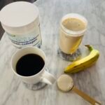 Coffee, collagen powder, protein smoothie, and banana on marble table