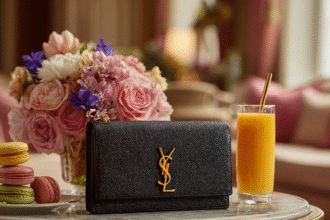 Black YSL clutch on a table with flowers, juice, and macarons