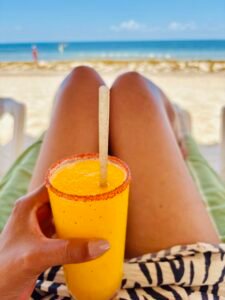 Mango smoothie with chili rim held on the beach with ocean view in Cancun.