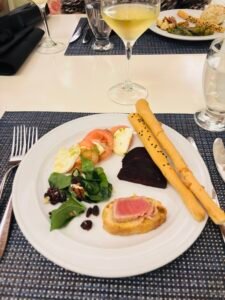 Gourmet dinner plate with seared tuna, caprese salad, beets, breadsticks, and white wine.