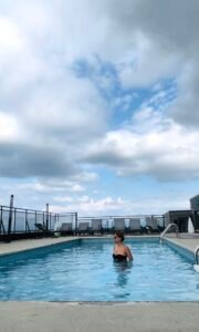 Woman enjoying a rooftop pool with city skyline views, representing luxury vertical living.