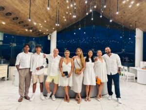 Group of family members dressed in white, celebrating together indoors.