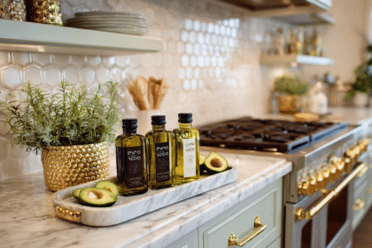 A beautifully organized kitchen counter with bottles of olive oil, fresh avocados, and gold-accented details.