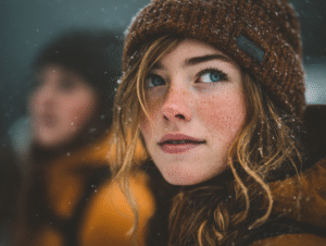 Close-up of a woman with freckles and blue eyes in a snowy setting, symbolizing depth, humanity, and lived experience in the age of automation.