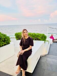 A woman sitting on a white terrace overlooking the ocean at sunset during a beach vacation.