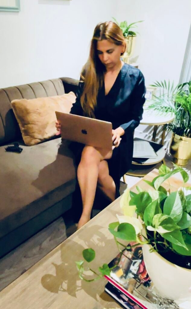 Woman sitting on a couch with a laptop, writing quietly at home as a form of self-expression and self-awareness.