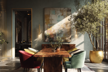 Rectangular wooden dining table with emerald, ivory, and burgundy velvet chairs and a large gold planter with olive tree