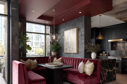 Burgundy velvet restaurant-style booth seating in a modern condo with black marble kitchen and pendant lighting