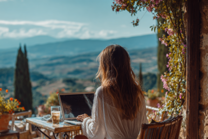 Woman working on a laptop outdoors overlooking mountains, representing time and location freedom through digital entrepreneurship.