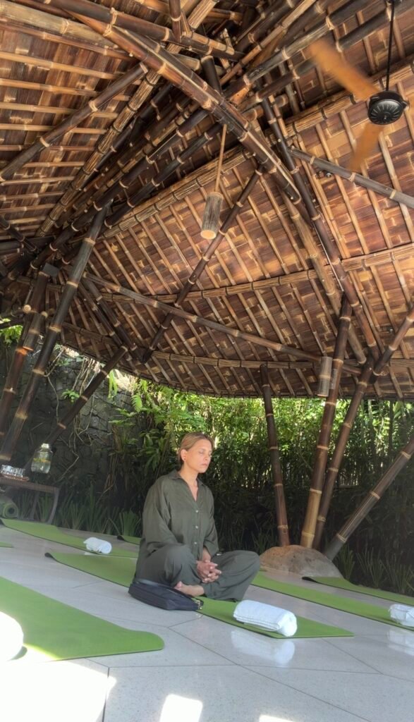 Woman meditating in a bamboo yoga pavilion surrounded by nature in Bali