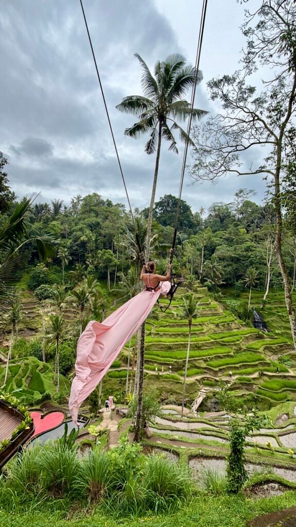 Woman on Bali swing overlooking rice terraces in Ubud