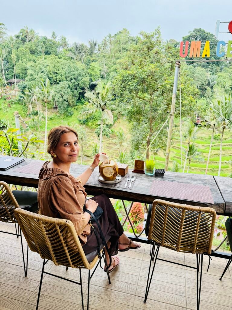 Woman enjoying coconut drink at a cafe overlooking rice terraces in Ubud Bali